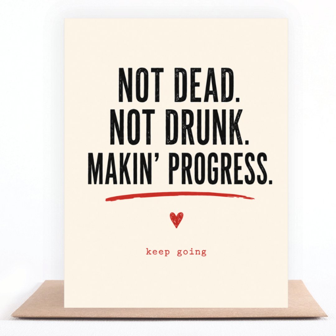 Not Dead, Not Drunk, Keep Going greeting card standing on a kraft envelope
