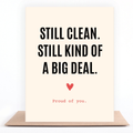 A cream-colored greeting card with bold black text reading 'STILL CLEAN. STILL KIND OF A BIG DEAL.