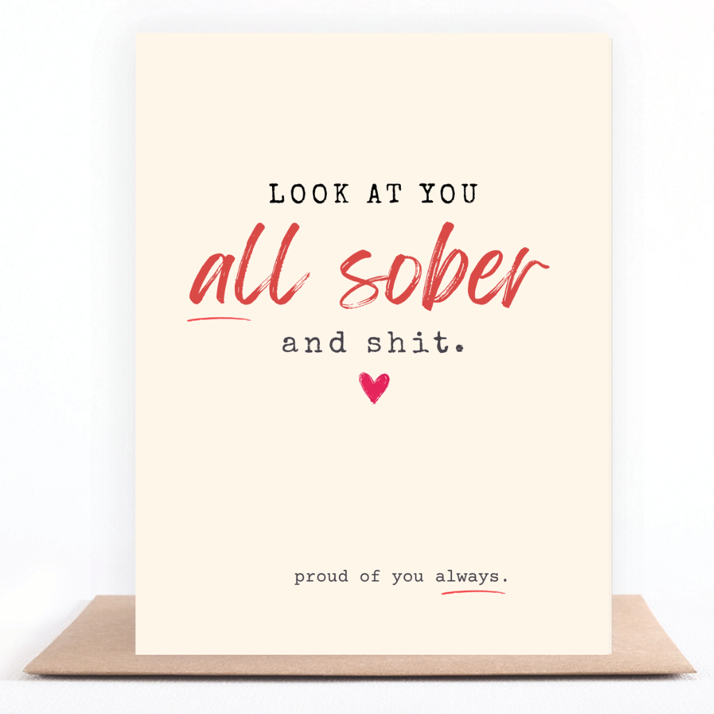A cream-colored greeting card with a humorous message, displayed on a brown kraft envelope against a white background. The card features the text 'LOOK AT YOU all sober and shit.