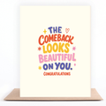 A cream-colored greeting card with colorful retro-style text reading 'THE COMEBACK LOOKS BEAUTIFUL ON YOU. CONGRATULATIONS', displayed upright on a brown kraft envelope against a white background.