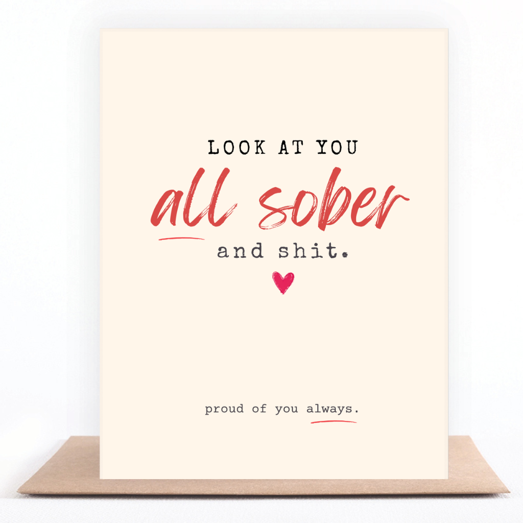 Funny cream, black, and red sobriety card reading “Look at You All Sober and Shit” and “Proud of You Always,” displayed with a kraft envelope.