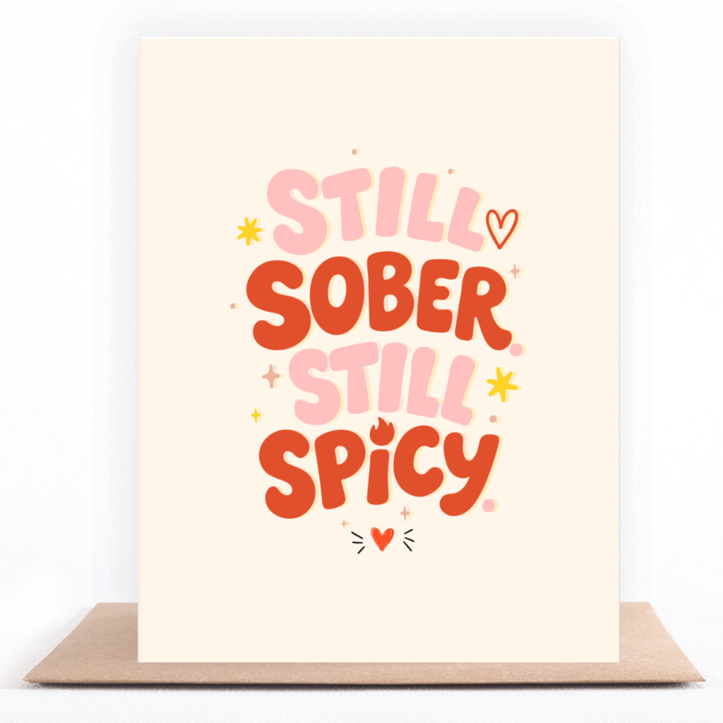 Colorful pink and orange sobriety card reading “Still Sober. Still Spicy.” displayed with a kraft envelope.
